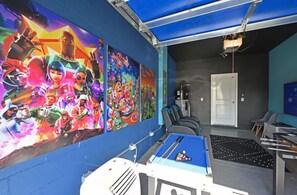 Una habitación con mesa de billar, proyector y murales coloridos en las paredes.