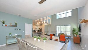 A spacious kitchen with a large island, modern pendant lighting, and a view to the dining area.