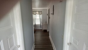 Un corridoio con pavimento rivestito di moquette, pareti bianche e una porta in fondo.