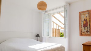 Quarto com cama, janela, luminária e um quadro na parede.