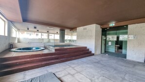 Ein geräumiger Innenbereich mit einer großen Whirlwanne, einem kleinen Pool und einer Treppe zu einer Tür.