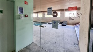 Eingangsbereich eines Spas mit Glastür, einem Schild für das Foza Palace Spa und einem Poolbereich, der durch die Scheibe sichtbar ist.