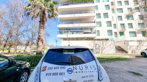 Ein weißes Auto mit einer Immobilienanzeige für NURIS IMMOBILIAIRIA, inklusive Kontaktdaten und einer Webseite.