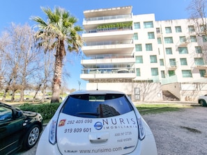 A white car with a real estate advertisement for NURIS IMMOBILIAIRIA, featuring contact numbers and a website.