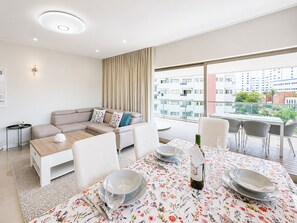 A modern living room with a sofa, coffee table, and dining area set for a meal.