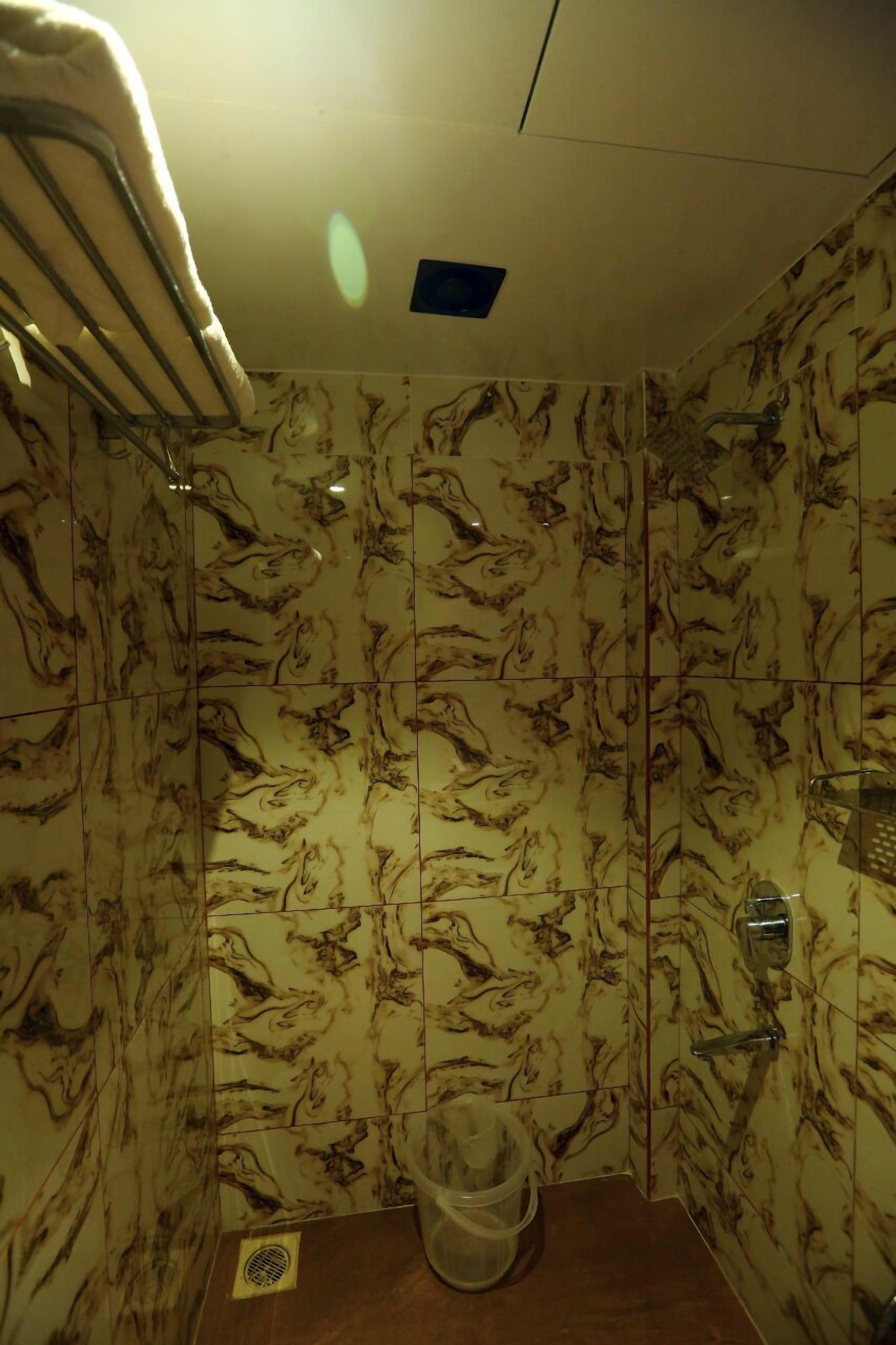 Un baño con paredes de diseño marmolizado, zona de ducha y un perchero para toallas.