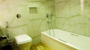 A bathroom with a marble wall, a toilet, a shower, and a bathtub. - Hotel Hindustan Residency (Thane)