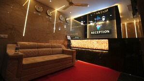 A reception area with a sofa, a reception desk, clocks, and a ceiling fan. - Hotel Hindustan Residency (Thane)