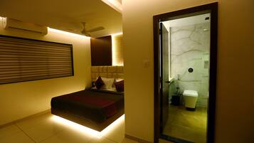 A modern hotel room with a bed, a ceiling fan, a bathroom with a marble wall, and a sliding door.