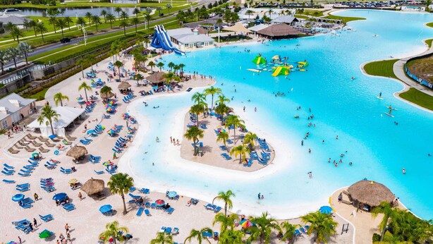 Ein Resort mit mehreren Schwimmbecken, einer großen Wasserrutsche und zahlreichen Liegestühlen und Sonnenschirmen.