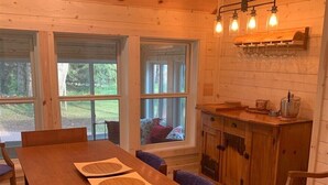 Ein Holzespeisekammer mit blau gepolsterten Stühlen, eine Holzschrank mit einer Pendelleuchte und große Fenster mit Blick ins Freie.