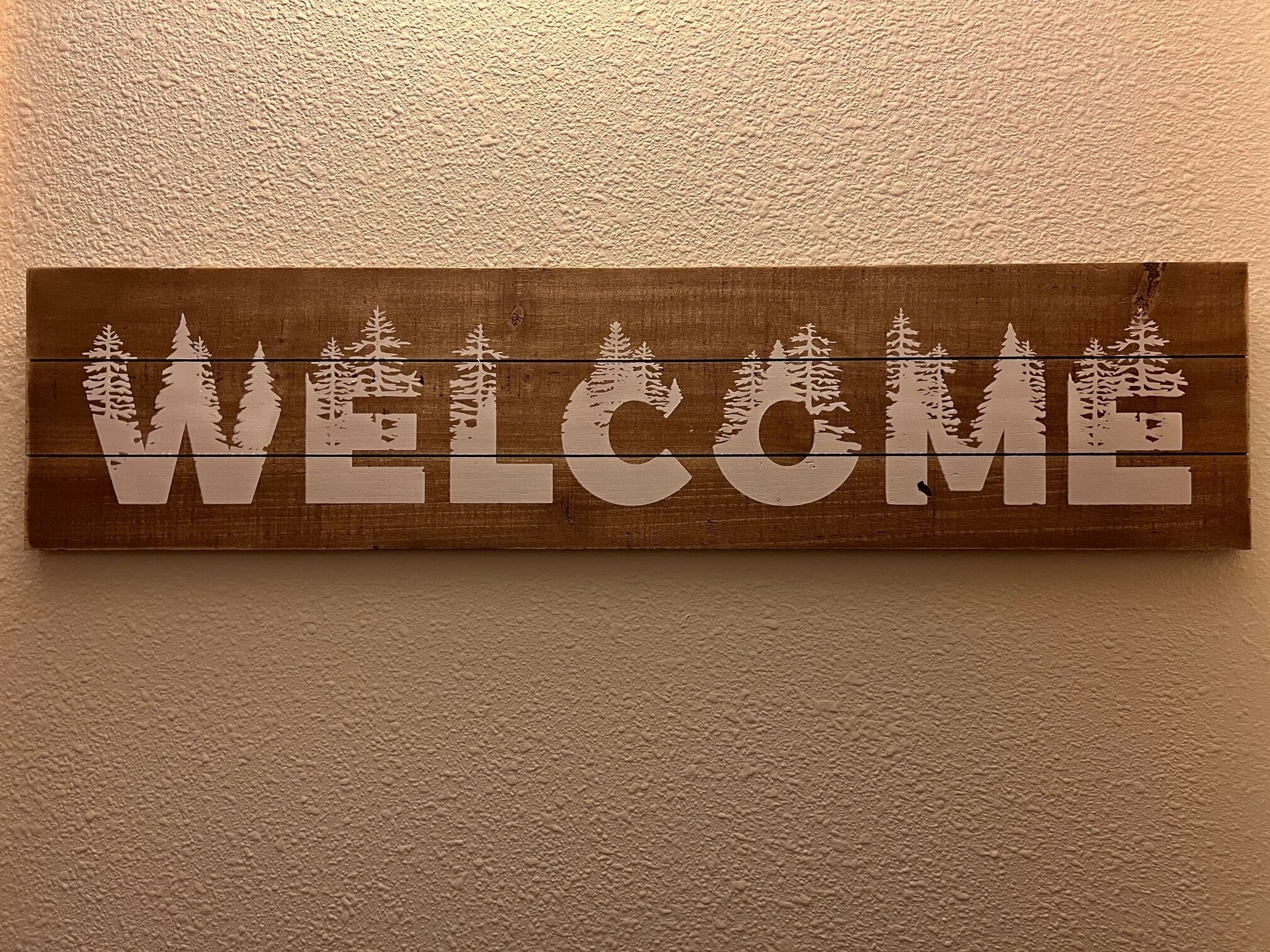 A wooden sign with the word "WELCOME" and tree silhouettes.