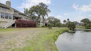 A residential area with a house featuring a front porch, a small staircase, and a manicured lawn. - 43 Fairway Dunes by AvantStay | Coastal Charm + Golf! (Isle Of Palms)