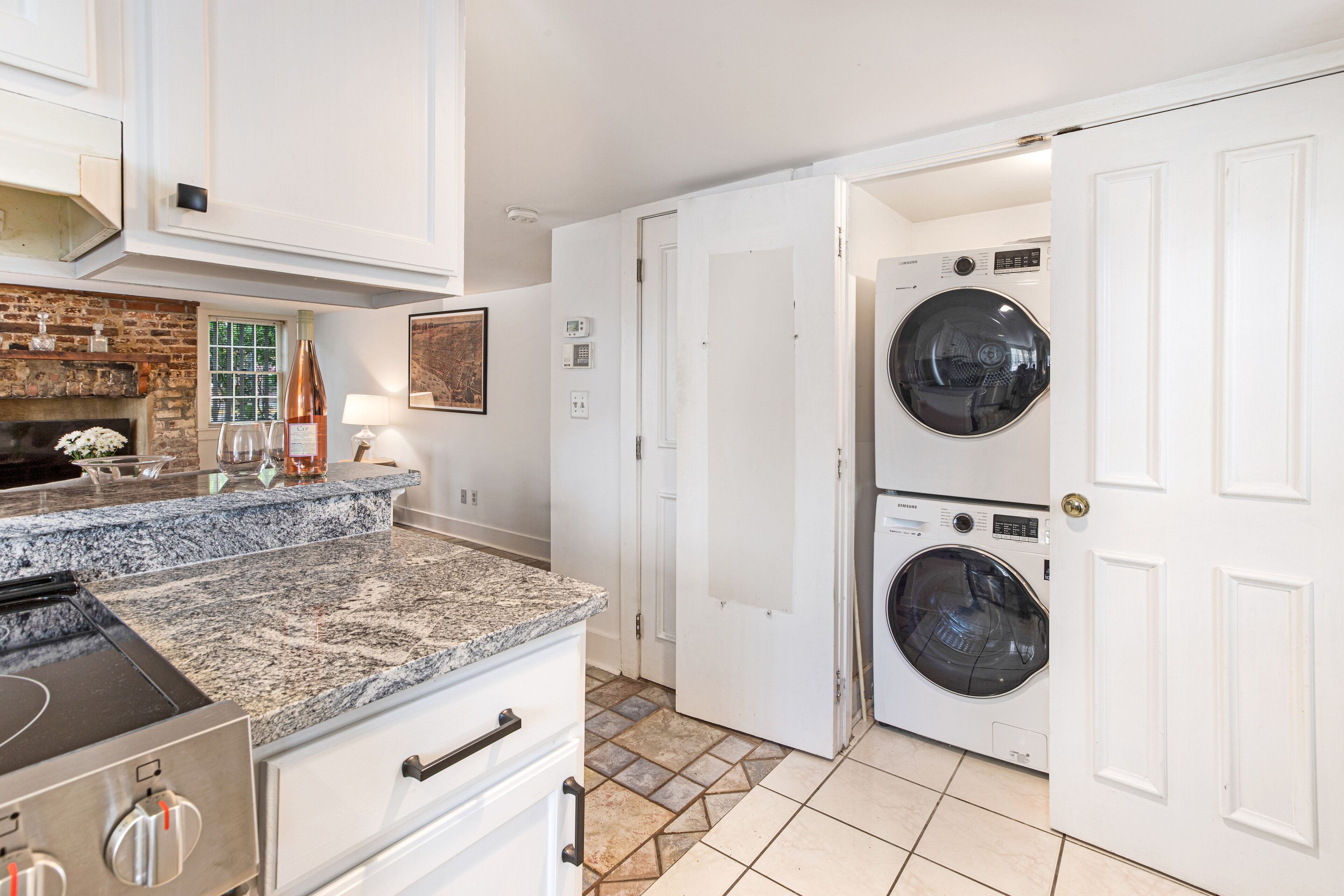 A kitchen with granite countertops, a stainless steel range, and a brick wall.
