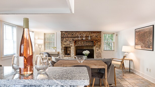 A modern kitchen with a marble countertop, a brick fireplace, and a dining area with a wooden table and chairs.