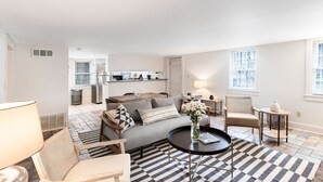 A modern living room with a sofa, armchairs, a coffee table, and a patterned rug.