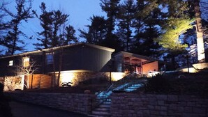 Ein zweistöckiges Haus mit einer Steinmauer und einer Holzterrasse.