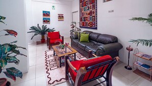 A living room with a sofa, armchair, coffee table, and potted plants. - KAARO HOTEL SUITE (Puno)