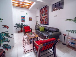 Una sala de estar con sofá, sillón, mesa de centro y plantas en macetas.