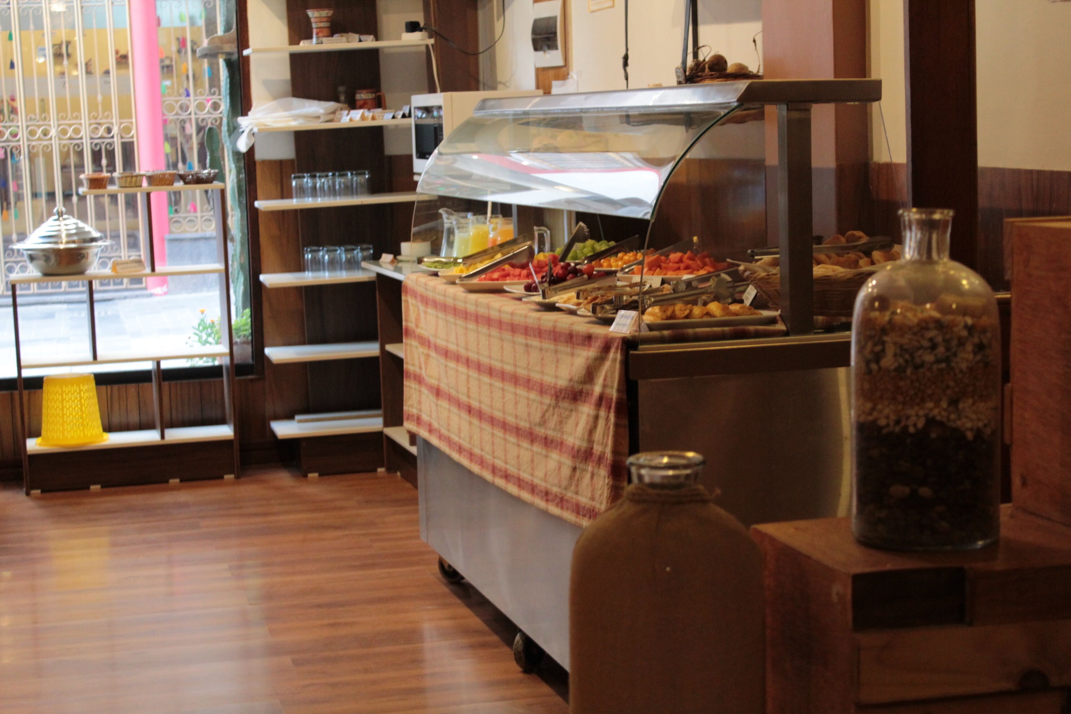 A buffet area with a variety of food items, a glass jar, and a metal container on a wooden counter.