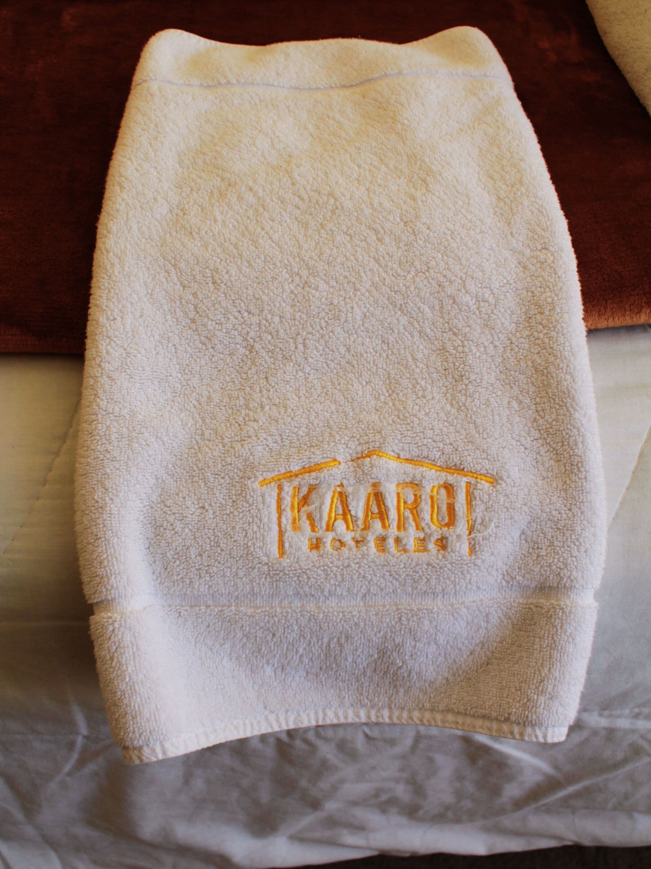 A white towel with a logo and text on it, placed on a bed.