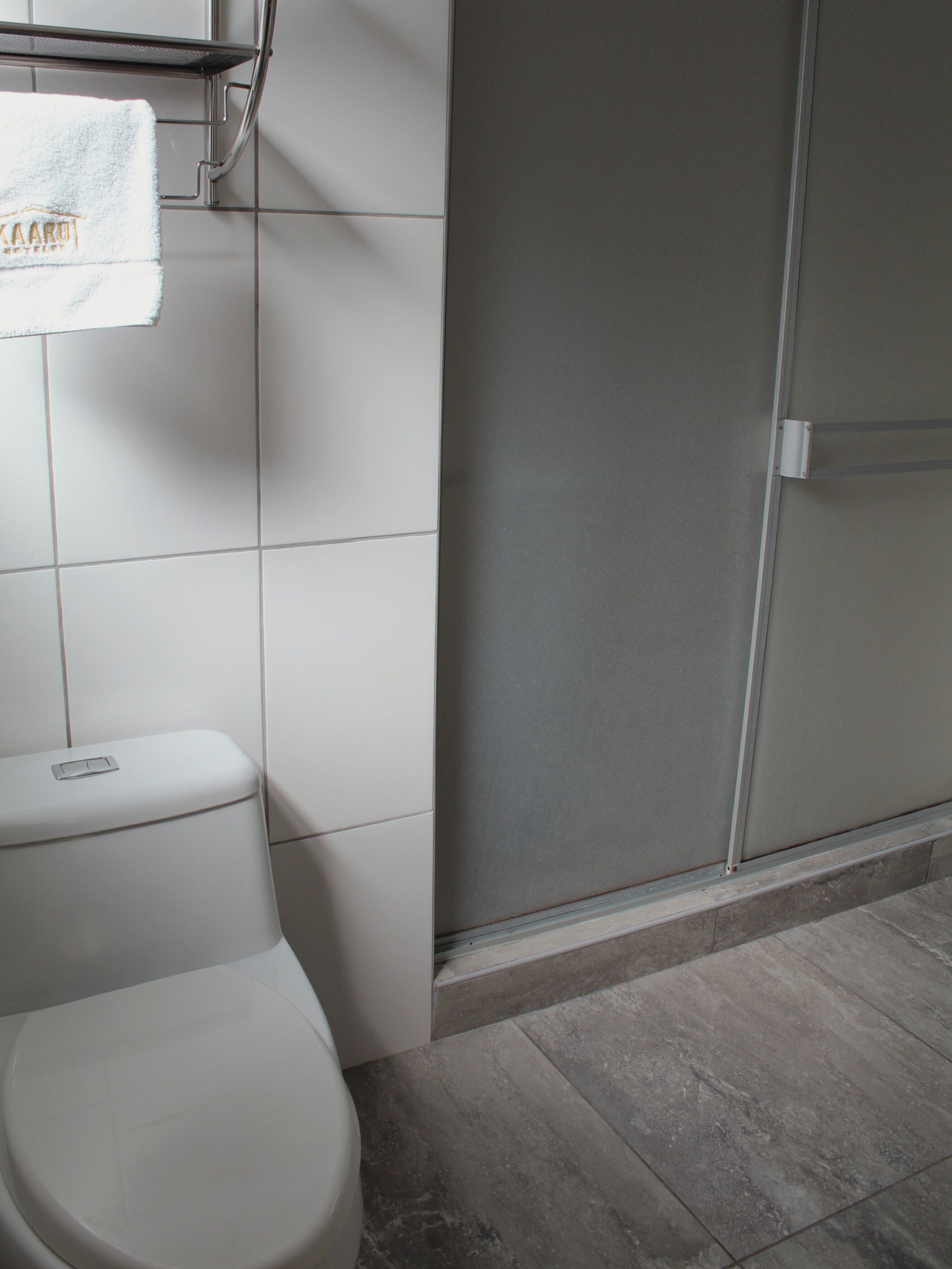 A bathroom with a toilet, a towel hanging on a rack, and a shower area.