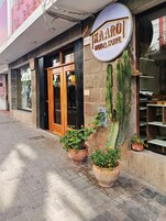 Entrada de un hotel con un cartel que dice 'KAARO HOTEL SUITE', una puerta de madera y plantas en macetas.