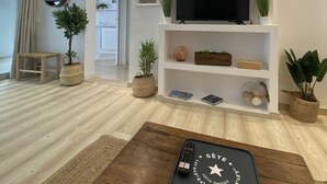 A modern living room with a flat-screen TV, wooden coffee table, and a remote control. - Sète! 50m2 new parking wifi quay Town center (Sète)