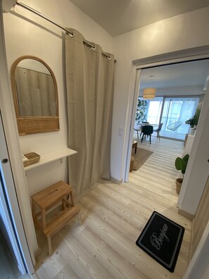 A modern bathroom with a wooden floor, a mirror, a shelf, a step, and a shower curtain.