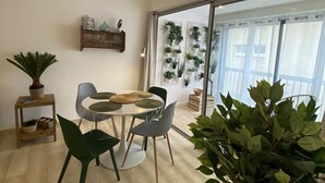 A dining area with a round table, four chairs, and a potted plant. - Sète! 50m2 new parking wifi quay Town center (Sète)