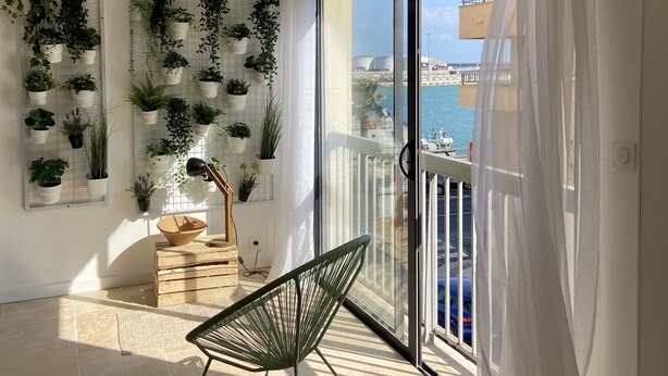 A balcony with a view of the sea, potted plants on the wall, and a chair. - Sète! 50m2 new parking wifi quay Town center (Sète)