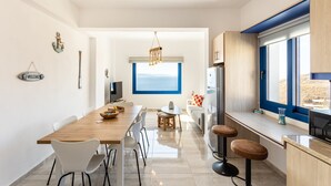 Una cucina moderna con un tavolo da pranzo in legno, sedie bianche, una zona bar e un'ampia finestra con vista.