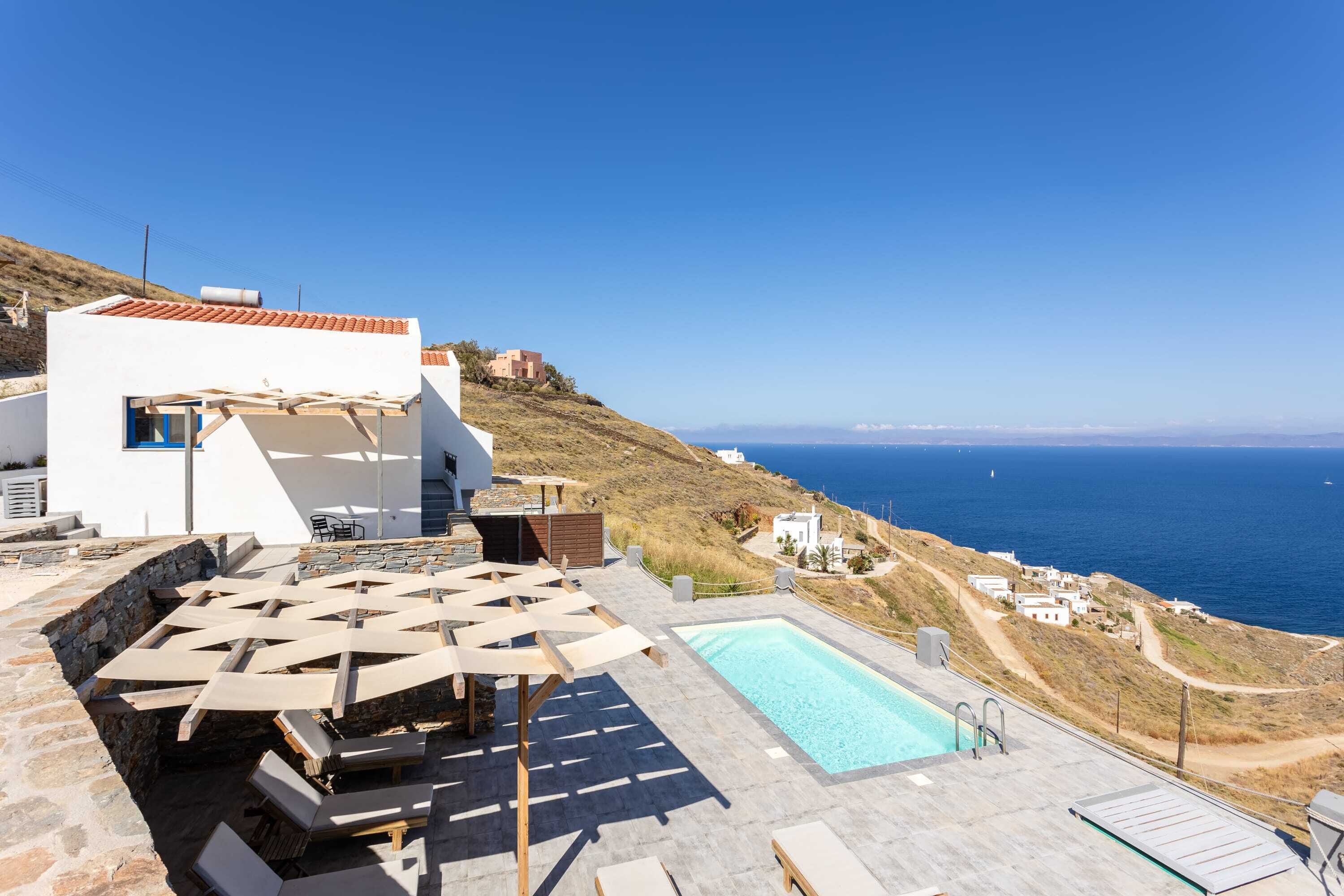 Un espace piscine aménagé sur le toit, avec des chaises longues et une piscine offrant une vue sur la mer.