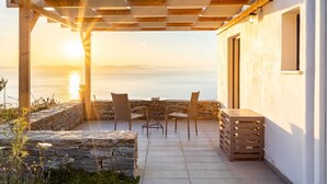 Une terrasse agrémentée d’une pergola, d’un escalier en pierre et d’une table avec des chaises, le tout offrant une vue sur la mer.