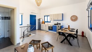 Une cuisine moderne avec des meubles de rangement bleus, une table à manger en bois et un luminaire suspendu.
