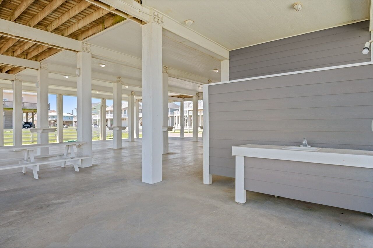A covered outdoor area with white benches and a grey wall.