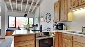 A modern kitchen with wooden cabinetry, a built-in oven, and a large island with a sink. - Summer Fun - SLOPESIDE 4BR/3BA with 3 Spas, Pool and Sauna - Perfect for Family and Friend Getaways All Year Round by RedAwning (Mammoth Lakes)