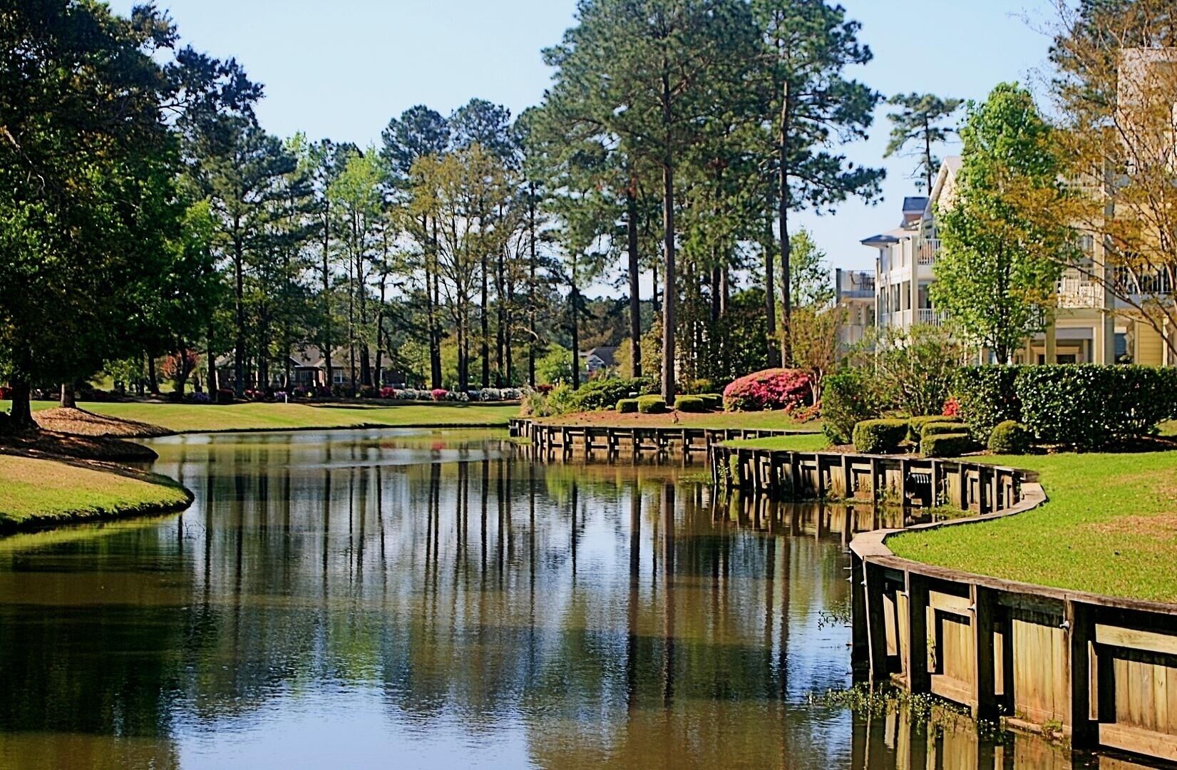 A golf course with a pond, wooden bridges, and surrounding trees.
