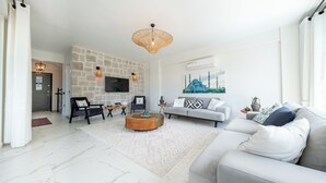Ein modernes Wohnzimmer mit Steinwand, Flachbildfernseher, grauem Sofa und Couchtisch.