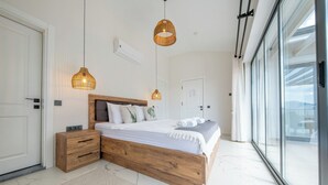Ein modernes Schlafzimmer mit einem hölzernen Bettgestell, weißer Bettwäsche und zwei hängenden Pendelleuchten.
