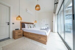 A modern bedroom with a wooden bed frame, white bedding, and two hanging pendant lights. - Olive Hills Villa Family-Friendly Luxury Villa with Private Pool in Fethiye (Fethiye)