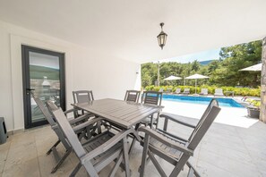 Une terrasse avec une piscine, des sièges d’extérieur et une vue sur le paysage environnant.