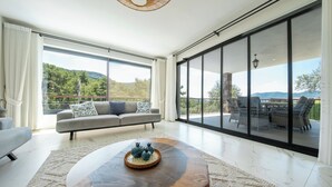 Ein geräumiges Wohnzimmer mit einem großen Schiebeglasfenster, das auf eine Außenpatio führt.