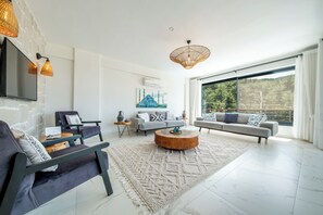 Un salon moderne avec une grande fenêtre, un ensemble de canapés, une table basse et un tapis décoratif.