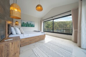A modern bedroom with a large window, a wooden bed frame, and a remote control on the nightstand. - Olive Hills Villa Family-Friendly Luxury Villa with Private Pool in Fethiye (Fethiye)