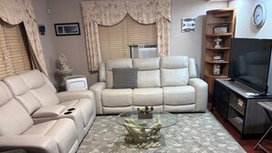 A living room with a sofa, a glass coffee table, a TV, and a bookshelf. - Spacious 2-bedroom apt in the Crest, 3 blocks from the beach (Wildwood Crest)