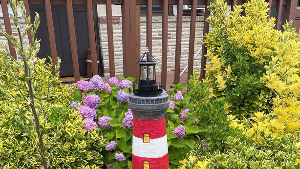 A garden with a painted lighthouse sculpture surrounded by various plants and flowers. - Spacious 2-bedroom apt in the Crest, 3 blocks from the beach (Wildwood Crest)