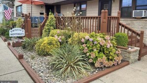A single-story house with a front porch, a small garden with various plants, and a sign indicating it's a rental property. - Spacious 2-bedroom apt in the Crest, 3 blocks from the beach (Wildwood Crest)