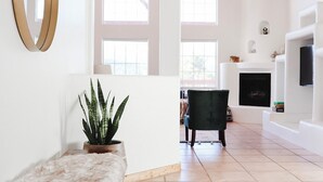 Een ruime woonkamer met een hoge plafond, een open haard, een grote spiegel en een potplant.