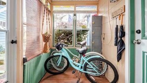 Une pièce étroite avec un vélo, une porte en bois et une vue par la fenêtre.